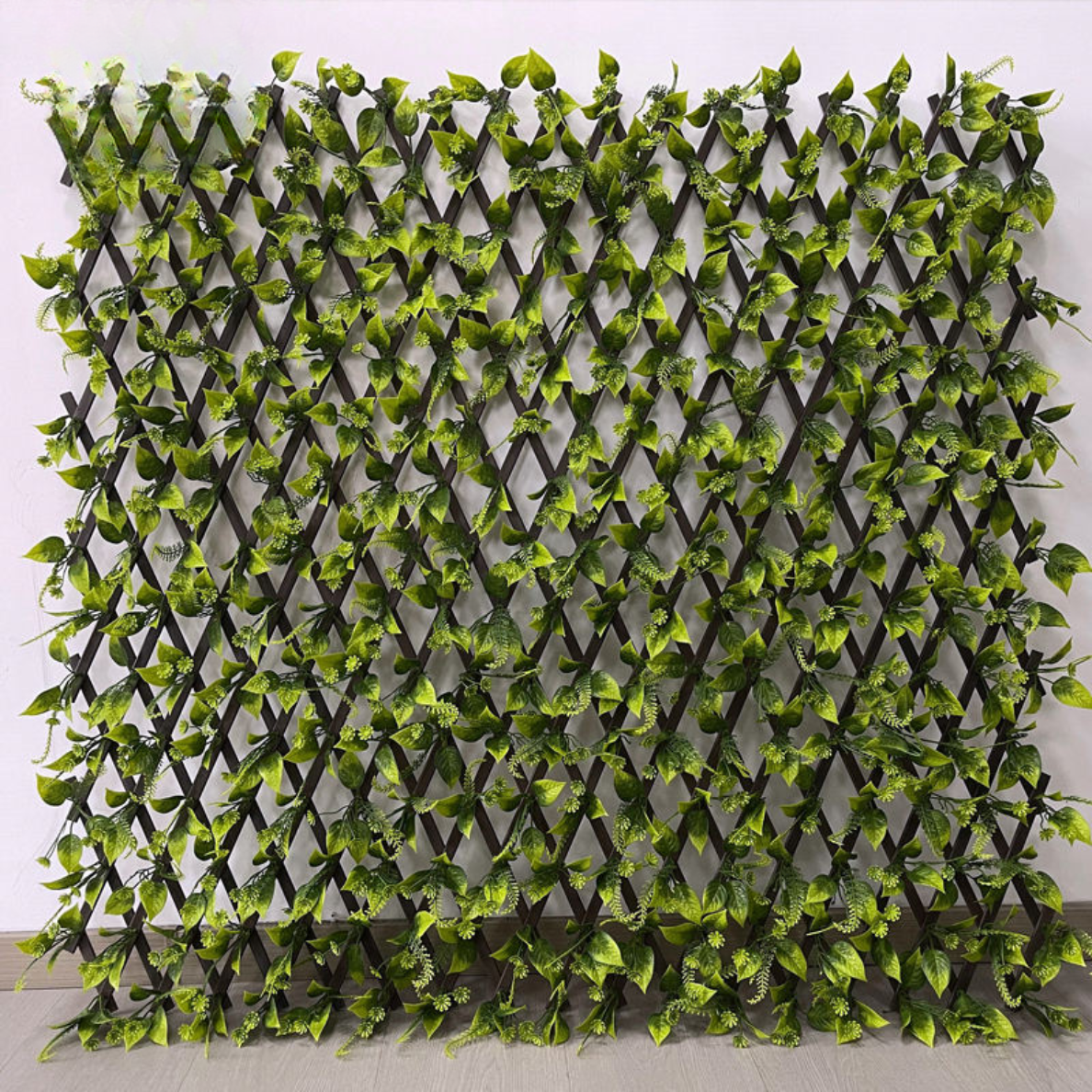 Artificial leaf trellis fence expanded into a green panel of dense PVC plastic foliage