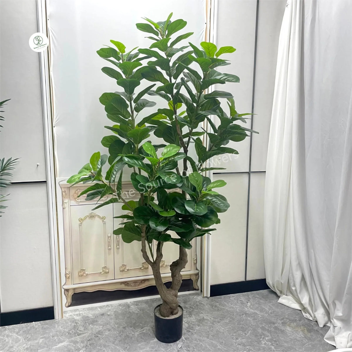 The faux ficus pandurata in a living room corner standing beside an armchair