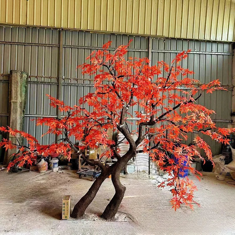 Large artificial red maple tree, crimson foliage spread across a wide open canopy