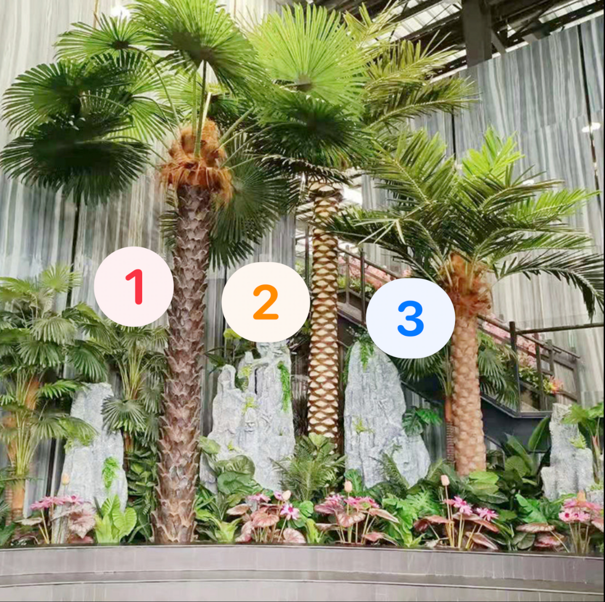 Large artificial palm on a metal trunk, broad fronds spreading at the crown