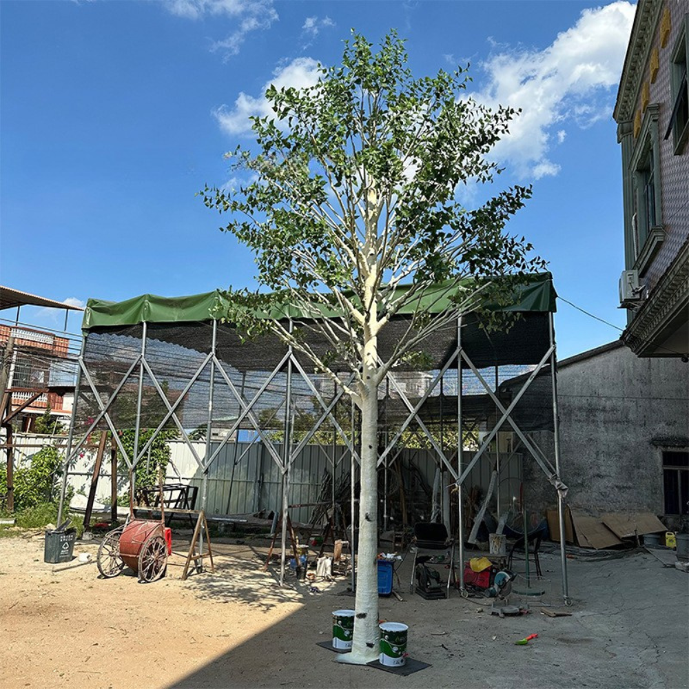 Large artificial birch tree, pale trunk rising under a light green leaf canopy