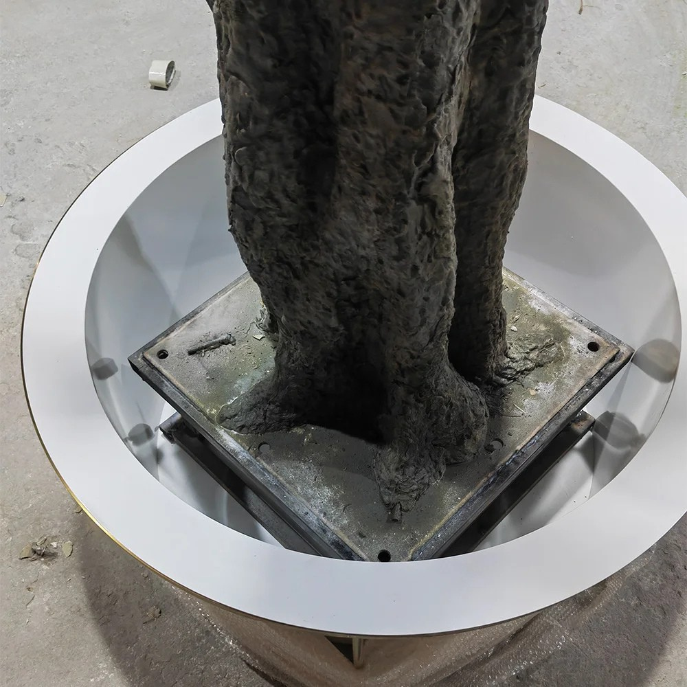 The white planter and base of the 4.8m artificial olive tree, topped with moss