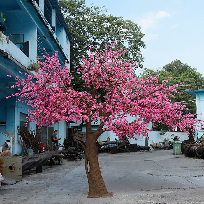 Artificial cherry blossom tree with pink blossom set on a natural wood trunk