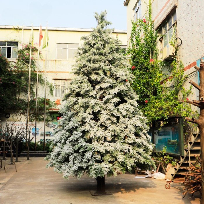 Artificial cedar tree 6ft tall with snow flocking across its evergreen branches