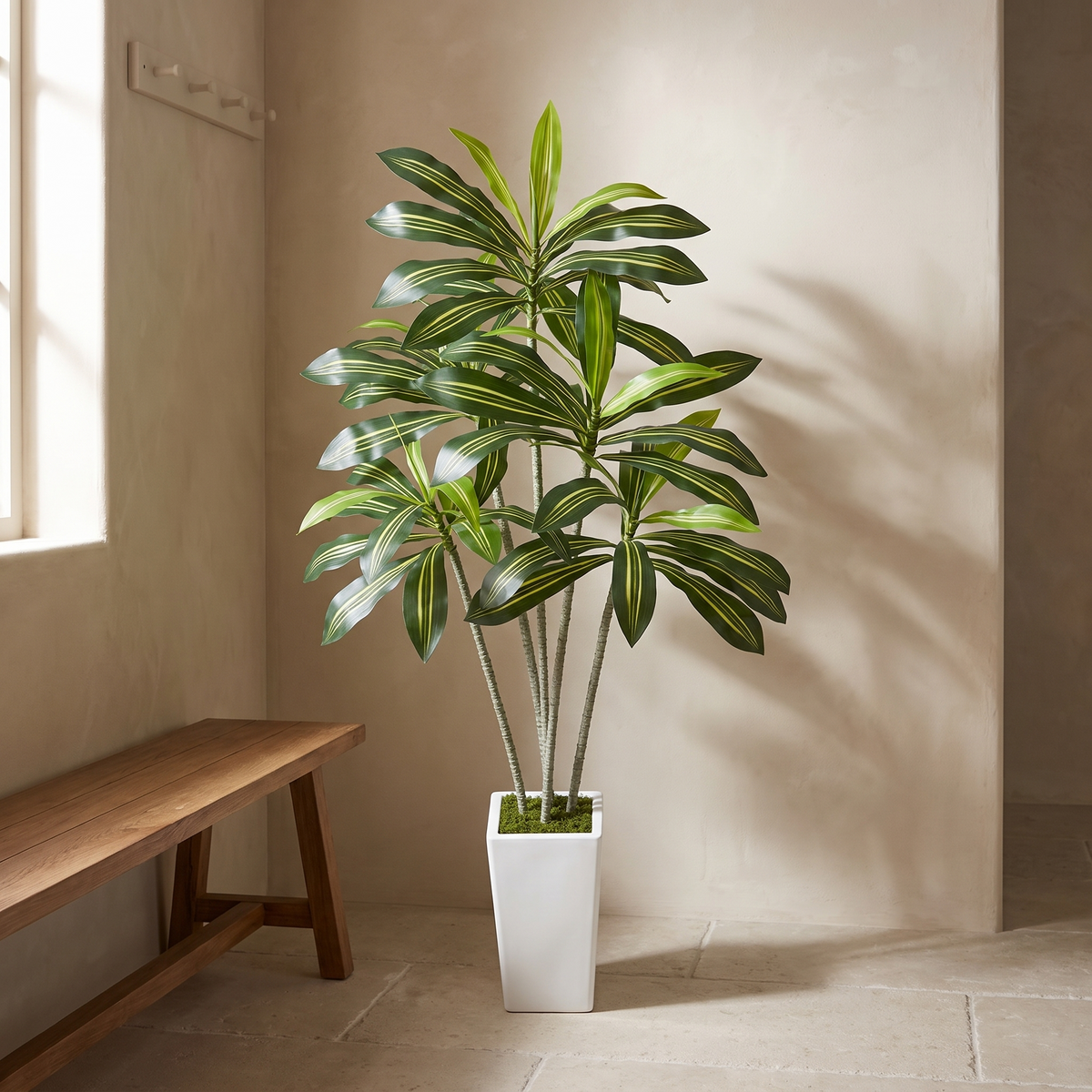 Artificial dracaena tree in a white planter topped with moss