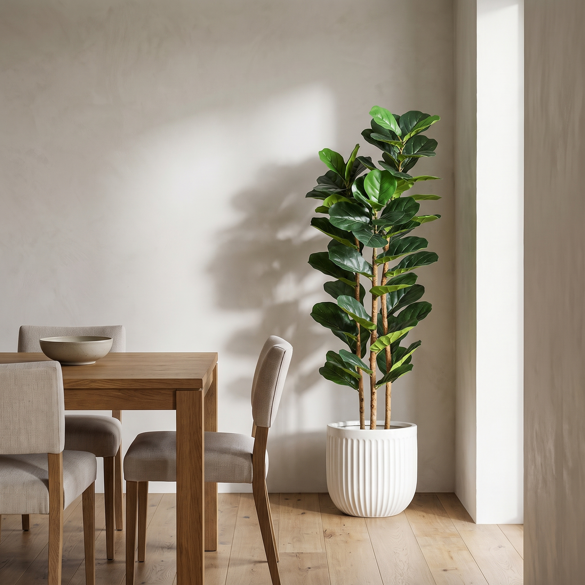 Artificial fiddle leaf fig tree with a real wood trunk in a white planter