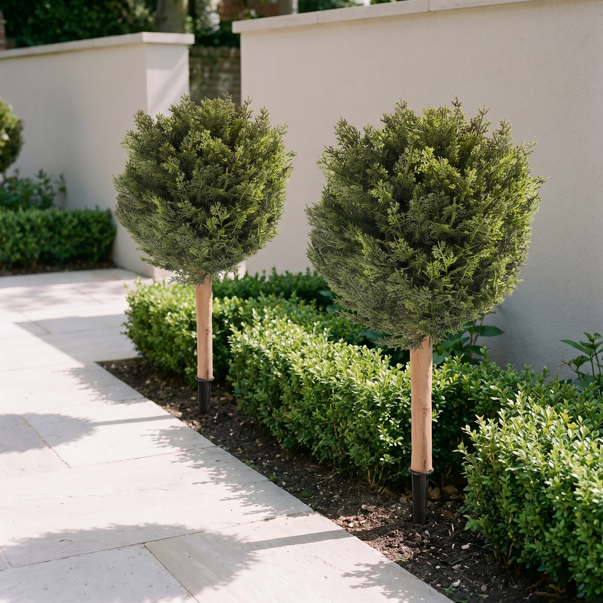 Pair of artificial cypress trees on ground spikes