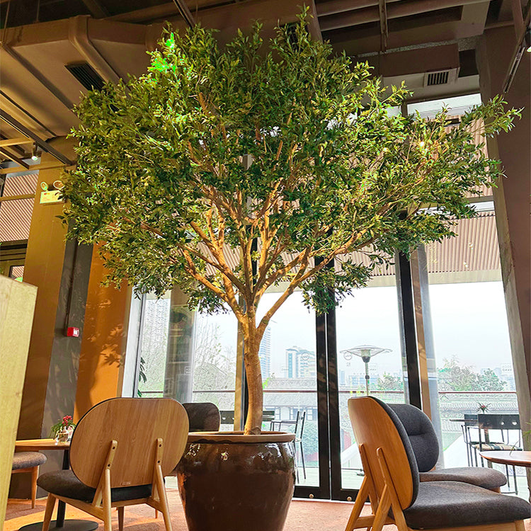 Large faux olive tree with silver-green Mediterranean foliage over a wide crown