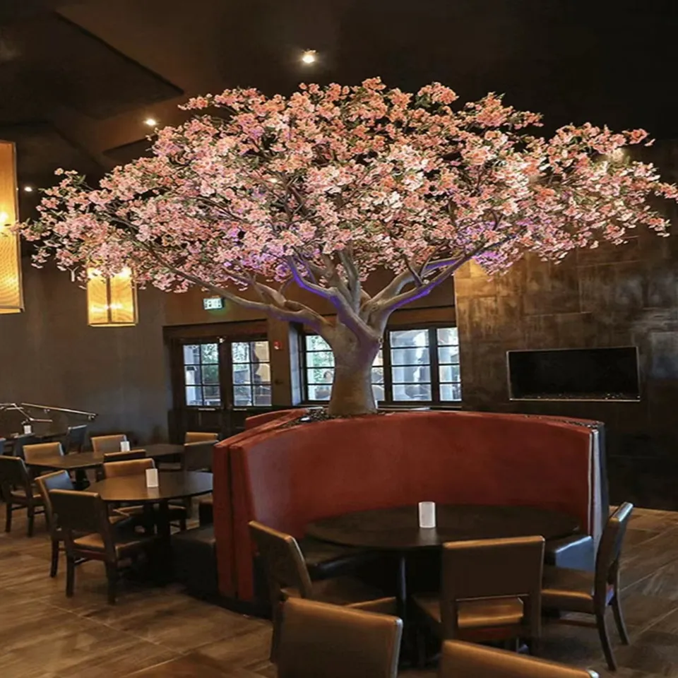 The same blossom tree in a hotel lobby, flowers spread above the seating
