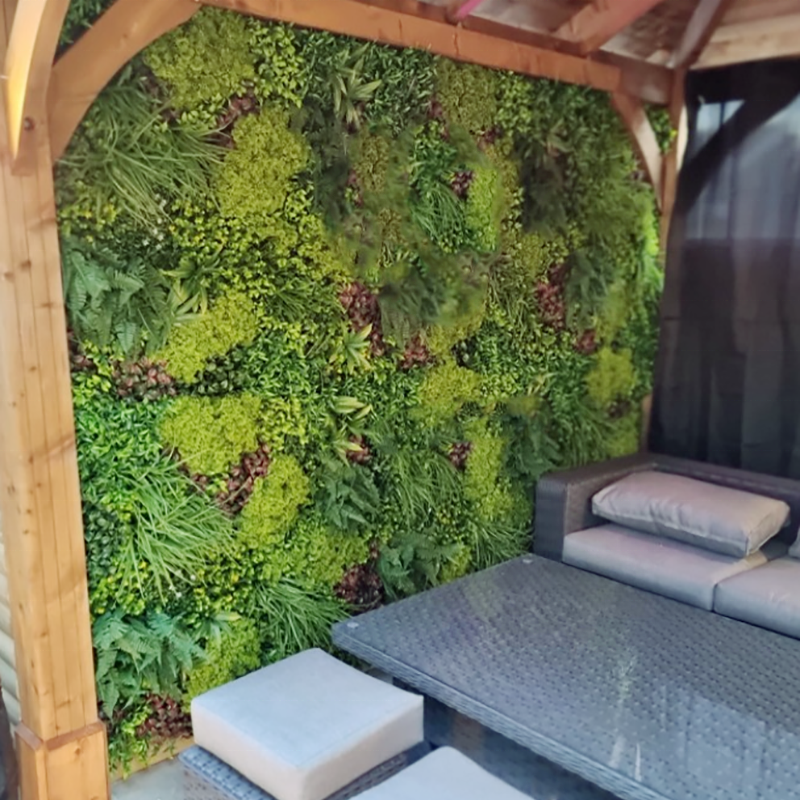 The boxwood plant wall used as a greenery backdrop behind a bar at an event